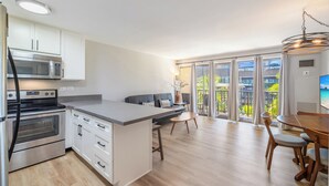 A modern kitchen with white cabinets, stainless steel appliances, and a large island.