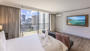 A hotel room with a large bed, a view of the cityscape, and a painting of a beach. - Partial Ocean View King STUDIO with Kitchenette and FREE WIFI! (Honolulu)