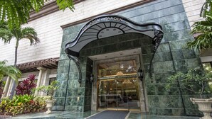 The entrance to The Royal Garden Wyndham Vacation Resorts Waikiki, featuring a grand archway and a well-maintained garden area. - Partial Ocean View King STUDIO with Kitchenette and FREE WIFI! (Honolulu)
