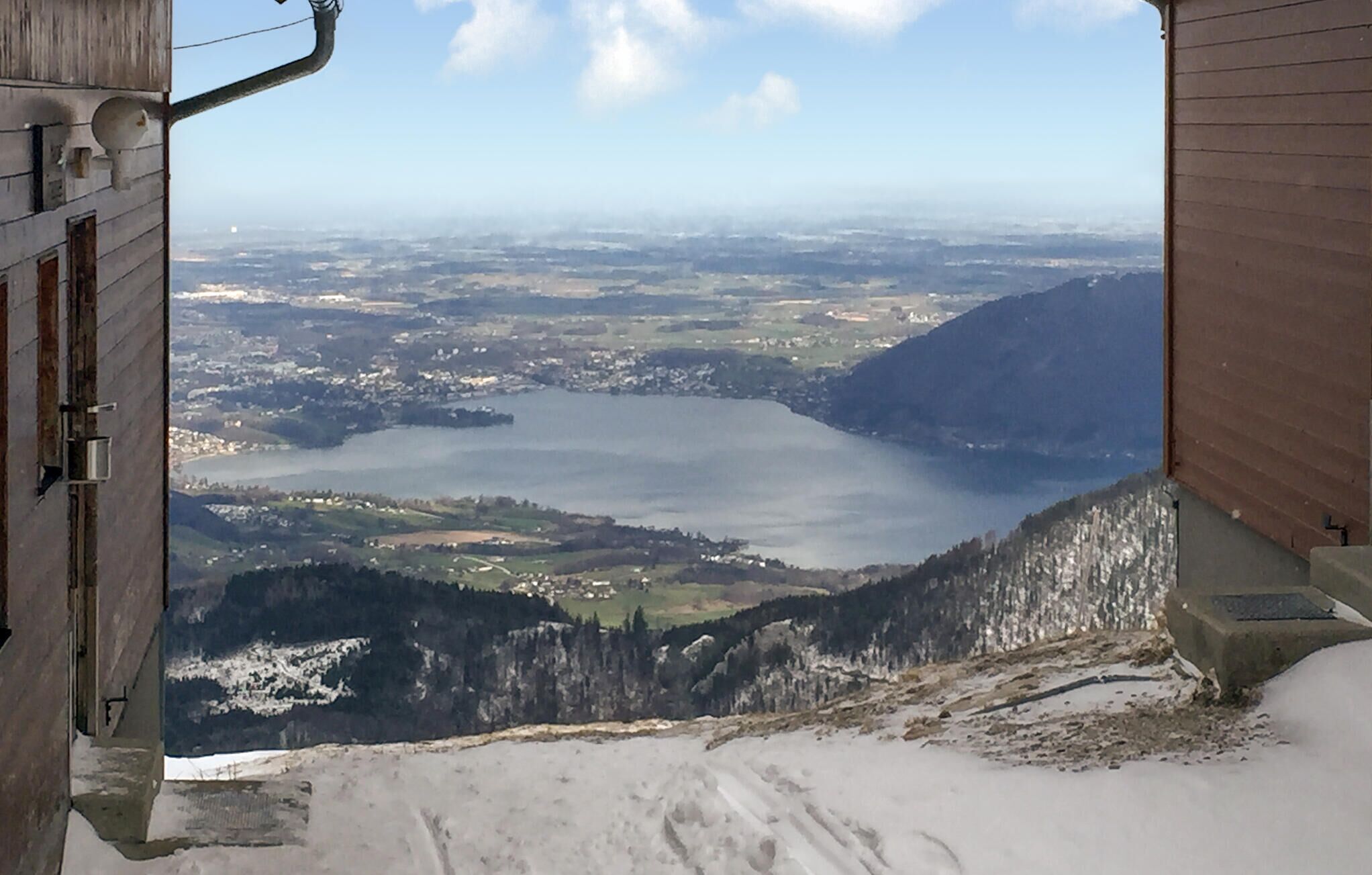 Aussicht von erhöhter Position auf einen See, der von Bergen und einer Stadt umgeben ist.