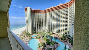A high-rise hotel with a pool area, beach view, and multiple balconies.