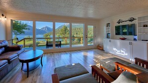 A spacious living room with a large sliding glass door leading to a deck with a mountain view.