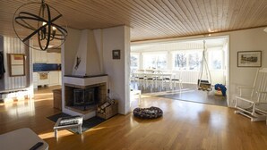 A spacious living area with a fireplace, wooden floors, and a dining area with white furniture. - Lovely home in Hakenäset with sauna (Hakenäset)
