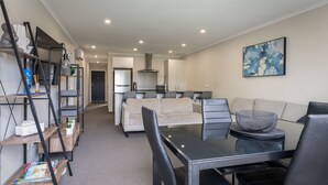 A modern living space with a sofa, dining table, and kitchen area. - Modern work-ready Hamilton home with sauna and EV charging (Waikato)