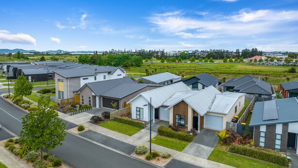 A residential area with modern houses, a clear sky, and a road. - Modern work-ready Hamilton home with sauna and EV charging (Waikato)