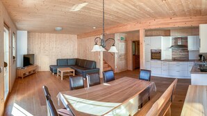 Een houten interieur met een eethoek, bank, televisie en keuken.