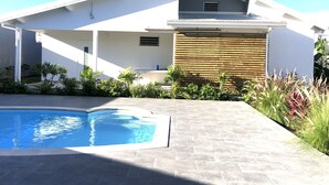 Ein modernes Haus mit Schwimmbad, einer überdachten Terrasse und einem Holzzaun.