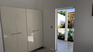 Ein Schlafzimmer mit Bett, Kleiderschrank und Blick auf Pool und Garten.