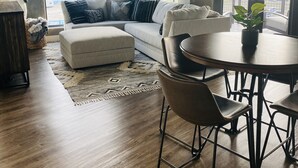 A modern living room with a sofa, ottoman, and dining table. - Prime Rental Location for Super Bowl LV Experience (Tampa)