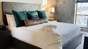 A bedroom with a large bed, dark headboard, and a view of the city through a large window. - Prime Rental Location for Super Bowl LV Experience (Tampa)