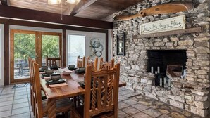 Comedor con chimenea de piedra, mesa de madera y sillas.