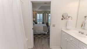 Une chambre d’hôtel avec un lit, une salle de bain comprenant un lavabo et un miroir, et une vue sur l’océan par la fenêtre.