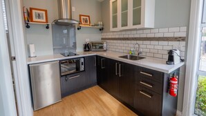 Une cuisine moderne dotée d’appareils électroménagers en acier inoxydable, de meubles de rangement aux couleurs sombres et d’un dosseret carrelé.