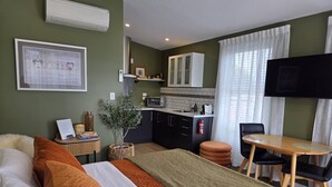 Une chambre d’hôtel de taille réduite comprenant un lit, une petite kitchenette, un coin repas et un téléviseur.