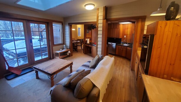 A compact living space with a skylight, wooden flooring, a sofa with cushions, a dining area, and a kitchenette. - Cozy Downtown Guesthouse (Silverton)