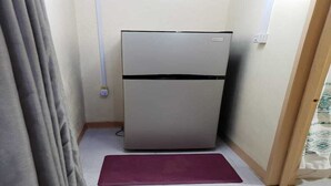 Een kleine keuken met een koelkast, een kleedje en een gordijn.