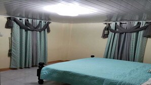 Een slaapkamer met een bed, gordijnen en een plafondventilator.