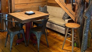 Un interior rústico de madera con comedor que incluye una mesa y sillas de madera, un banco acolchado y una escalera con barandilla de madera.