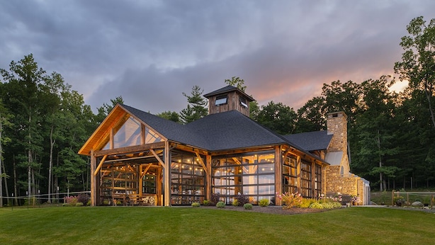 A large, rustic lodge with a stone chimney, expansive windows, and a well-maintained lawn.