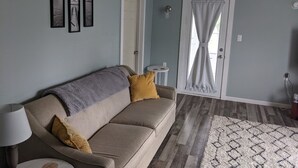 A living room with a sofa, a lamp, a rug, and framed pictures on the wall.
