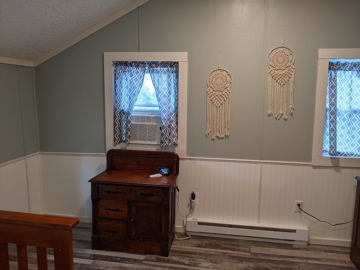 Una habitación con un escritorio de madera, un calentador en la pared y atrapasueños decorativos.
