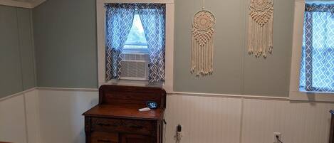 Una habitación con un escritorio de madera, un calentador en la pared y atrapasueños decorativos.