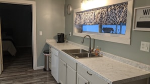 A kitchen with a double sink, a coffee maker, and a clock on the wall.