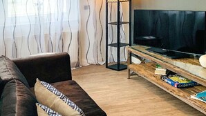 Ett vardagsrum med en soffa, en tv placerad på ett träbord och en golvlampa.