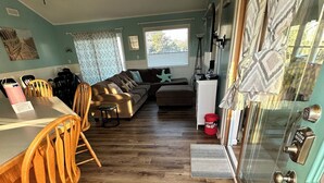 Eine Küche mit Holzboden, einem Essbereich mit Holzstühlen, einem Deckenventilator und einem Fenster mit Jalousien.
