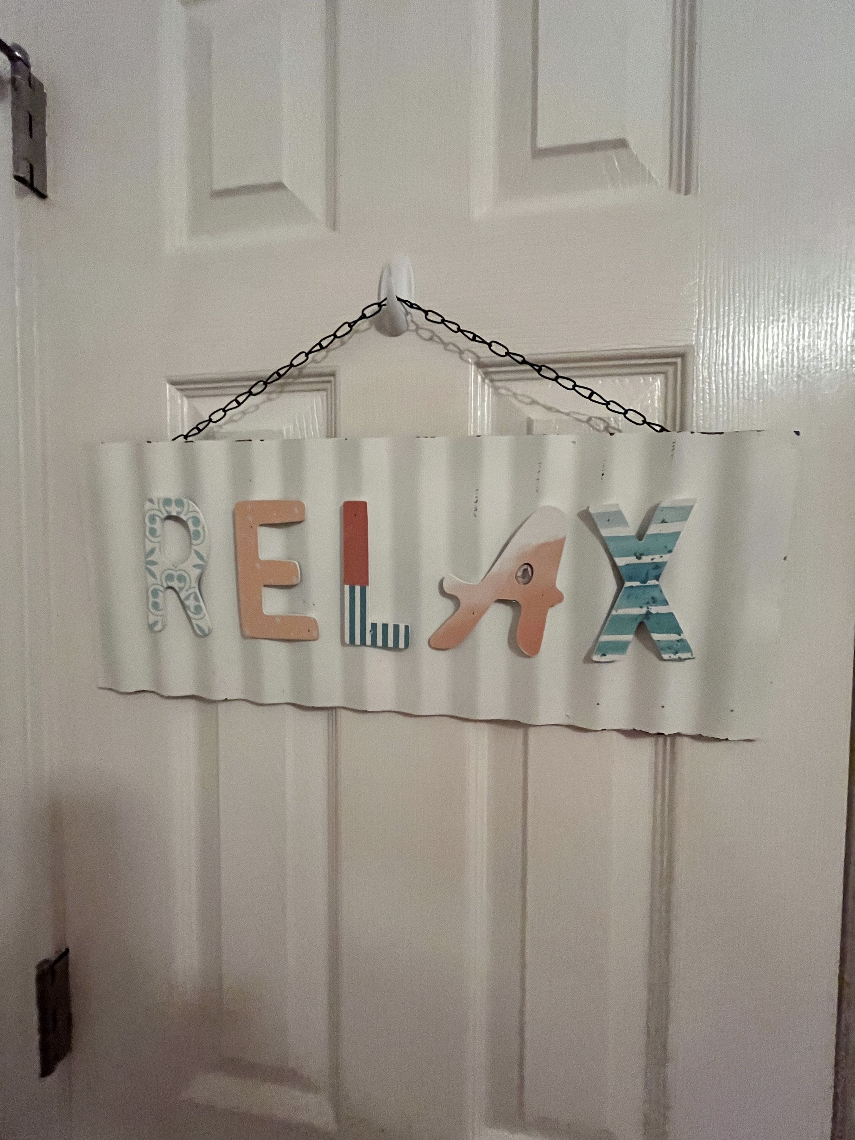 A white door with a 'RELAX' sign hanging on it.