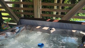 Ein Whirlpool mit einer Holzterrasse und einem Holzzaun im Hintergrund.