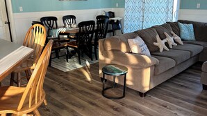 Ein Wohnzimmer mit einem Holzesstisch, Stühlen, einem Sofa und einem Couchtisch.