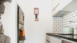 A compact kitchen with white cabinets, a built-in oven, a dishwasher, and a tiled backsplash.