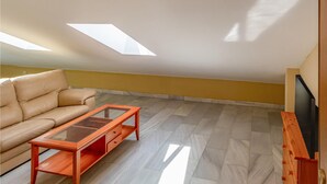 A spacious living area with a high ceiling, a sofa, a glass-top coffee table, and a television. - Lovely apartment in Málaga with WiFi (Málaga)