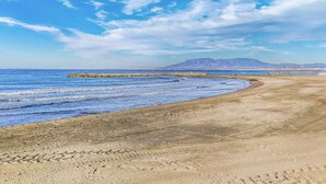 A beach with a rocky breakwater, clear blue sky, and distant mountains. - Lovely apartment in Málaga with WiFi (Málaga)