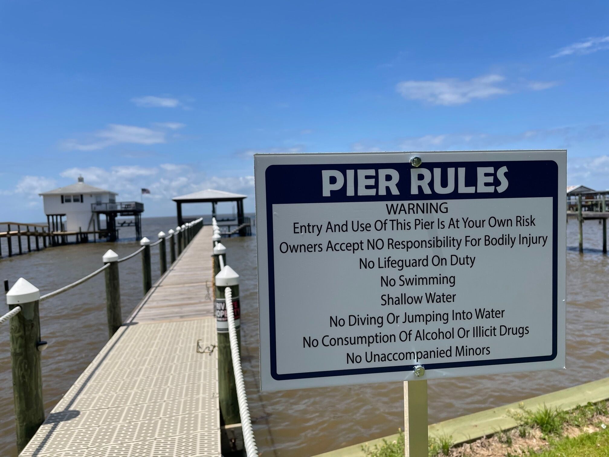 Un muelle con un cartel que enumera las normas y advertencias del muelle.