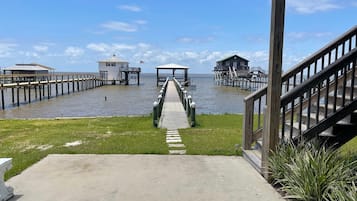 A pier leading to a wooden structure with a covered area, a small white building, and a larger wooden building with a green roof.