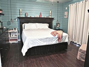 Cozy retreat with a dark wooden bed, white bedspread, and a dresser with a mirror.