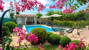 Un patio trasero con piscina, sillas de descanso y un área de patio cubierta.