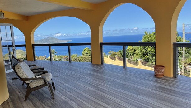 Un balcon avec vue sur la mer, doté d’un plancher en bois et d’une chaise.