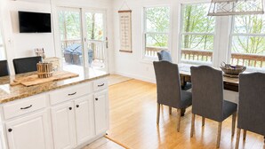 A kitchen with white cabinets, a granite countertop, and a dining area with grey chairs. - Lakefront, 3 Amazing Decks, Tennis/Pickle Ball, Boat Slip, Hot Tub, Bed Swing
 (Oakland)