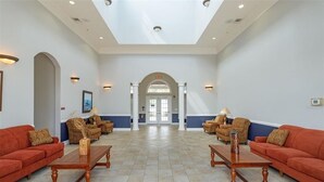 A spacious lobby with a high ceiling, a central archway, and a symmetrical arrangement of sofas and tables. - Homely spacious 2BD Close to Disney (Kissimmee)