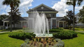 A building with a fountain in the center surrounded by a garden with various plants and flowers. - Homely spacious 2BD Close to Disney (Kissimmee)