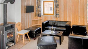 Een knusse woonkamer met een open haard, lederen meubels, een televisietoestel en een raam met behang.