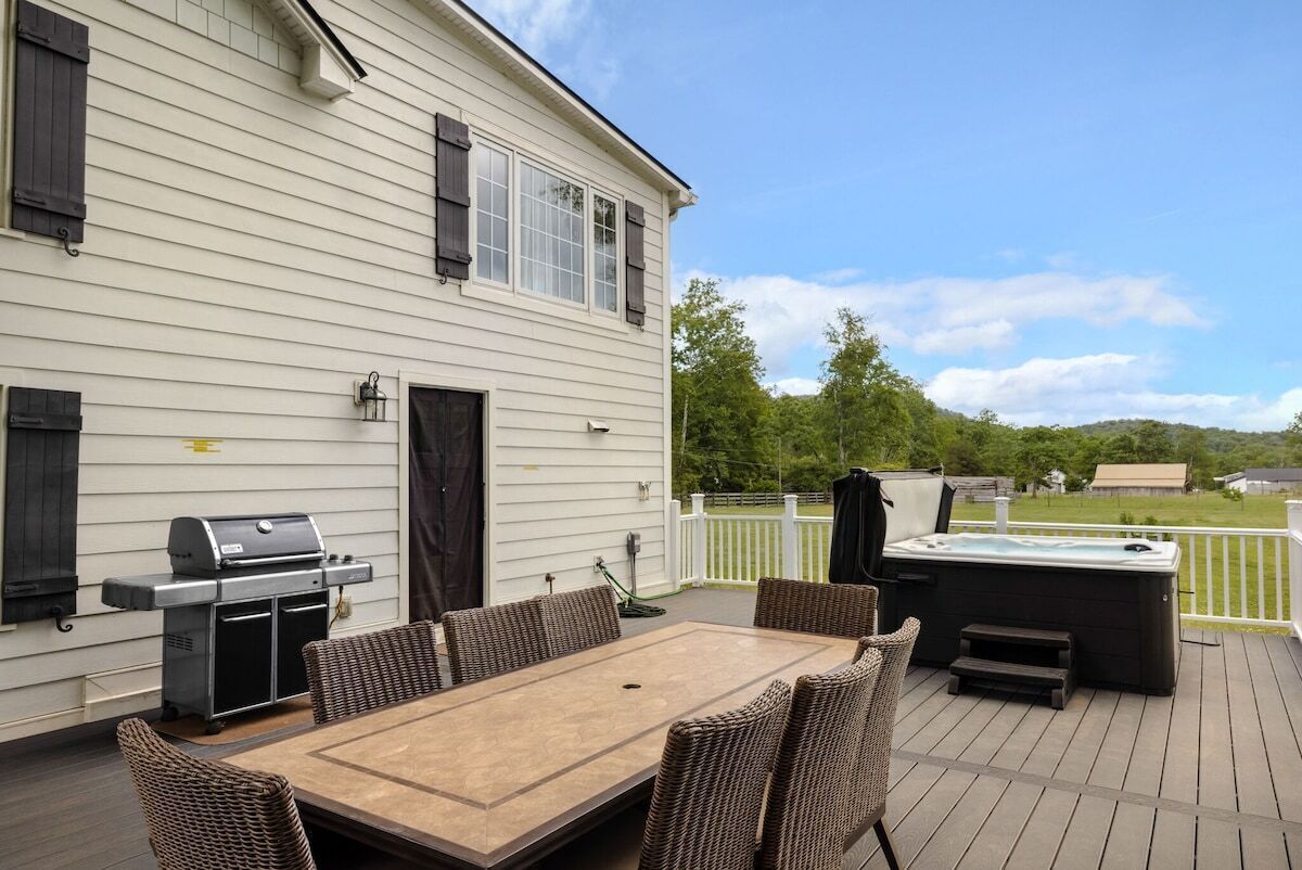 Une terrasse avec une table et des chaises, un barbecue et un jacuzzi.