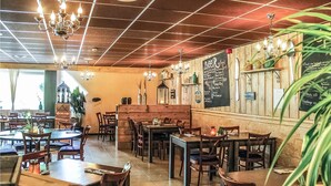 A restaurant interior with wooden tables and chairs, a high ceiling with chandeliers, and a chalkboard menu on the wall. - 3 bedroom stunning home in Gramsbergen (Gramsbergen)
