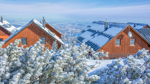 A wooden cabin with a sloped roof, surrounded by snow-covered trees, and a view of a distant landscape. - Ferienhaus mit Bergpanorama (Ebensee)