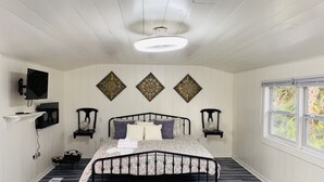 Un dormitorio con cama, televisor montado en la pared, decoración mural y una ventana.