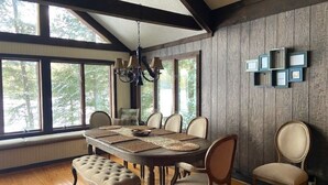 A dining area with a wooden table, chairs, and a chandelier. - Private Lake Front Adirondack Retreat on Loon Lake-20 Min from Lake George, Gore (Chestertown)