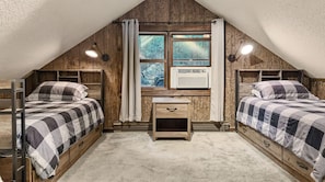 A bedroom with two beds, a window with a view, a heater, and a small wooden nightstand.